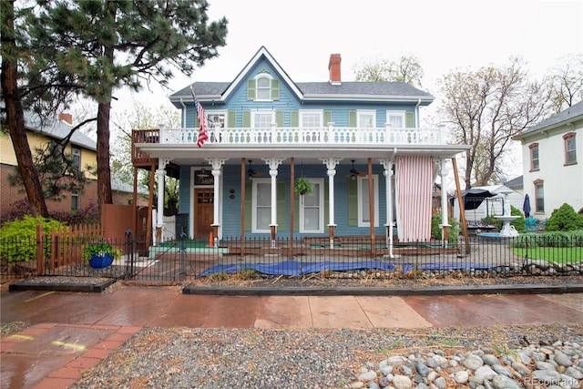 2627 Champa St, Denver, CO 80205 - view of front of house with a porch, a ceiling fan, a fenced front yard, a chimney, and a balcony