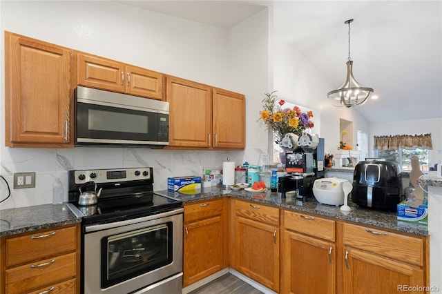 kitchen with backsplash, decorative light fixtures, hardwood / wood-style floors, stainless steel appliances, and vaulted ceiling