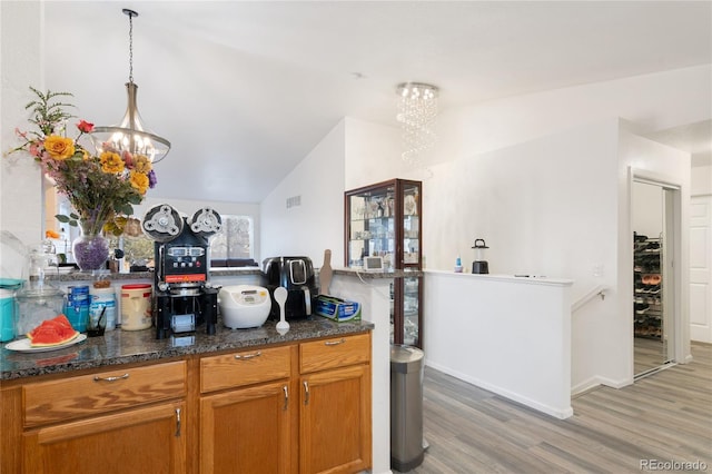 kitchen featuring decorative light fixtures, vaulted ceiling, a chandelier, and light wood-type flooring