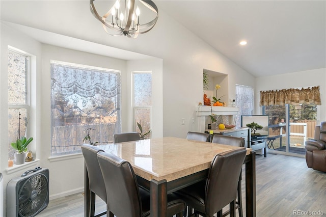 dining space with lofted ceiling, hardwood / wood-style floors, and a chandelier