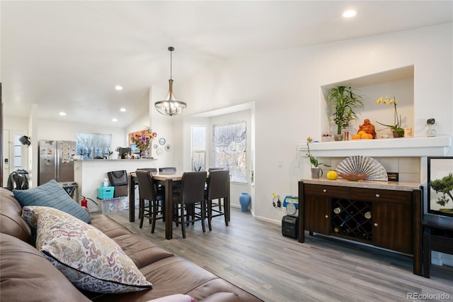 living room with wood-type flooring, lofted ceiling, and a chandelier