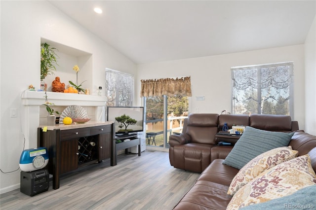 living room with vaulted ceiling, light hardwood / wood-style floors, and a healthy amount of sunlight