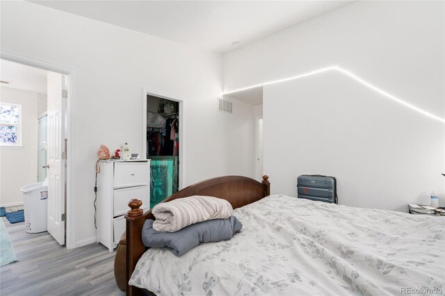 bedroom with wood-type flooring, connected bathroom, and a closet