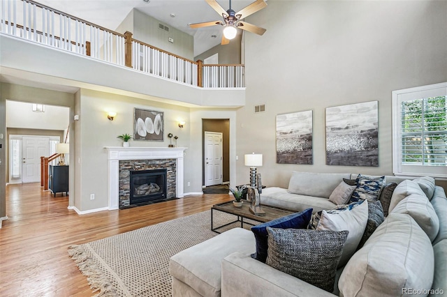 3411 Springbriar Dr, Castle Rock, CO 80109 - living area with wood finished floors, a ceiling fan, a high ceiling, baseboards, and a stone fireplace