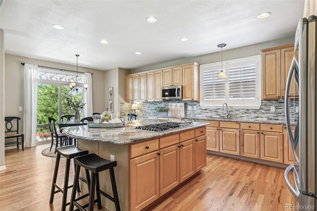 3411 Springbriar Dr, Castle Rock, CO 80109 - kitchen with appliances with stainless steel finishes, a breakfast bar area, light stone countertops, tasteful backsplash, and light wood-style flooring