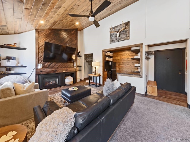 living room featuring lofted ceiling, wood ceiling, a large fireplace, carpet floors, and ceiling fan