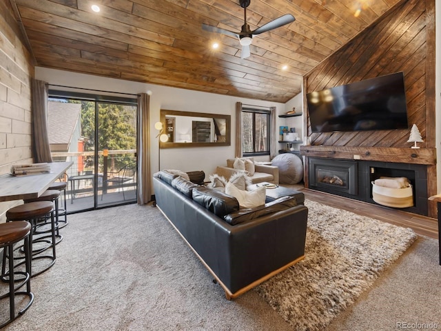 living room with ceiling fan, carpet floors, a fireplace, and wood ceiling