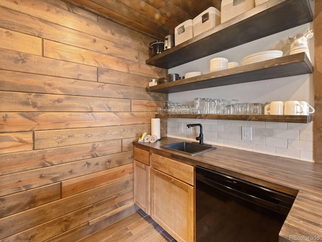 bar featuring black dishwasher, sink, butcher block countertops, and wood walls