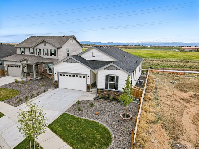 view of front of home with fence, a shingled roof, an attached garage, stone siding, and driveway