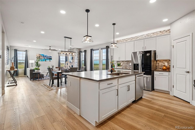 kitchen with dark countertops, tasteful backsplash, a sink, stainless steel appliances, and light wood-style flooring