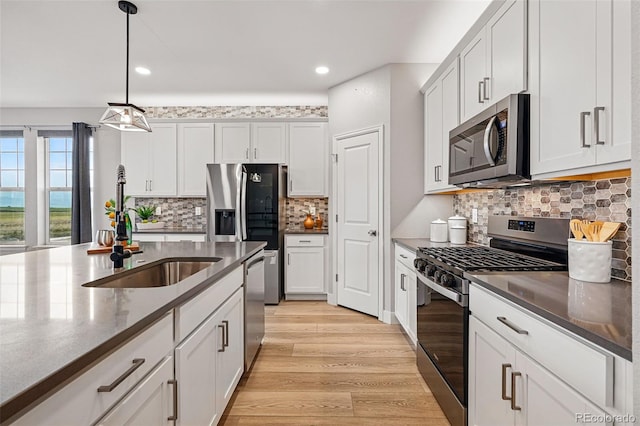 kitchen featuring a sink, light wood finished floors, stainless steel appliances, decorative light fixtures, and recessed lighting