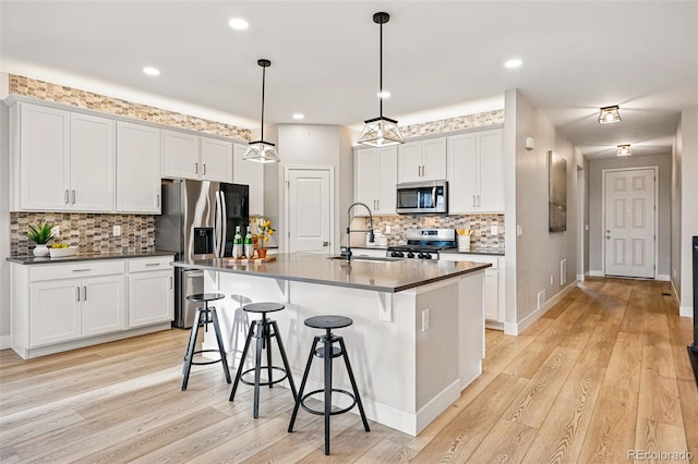 kitchen featuring a sink, appliances with stainless steel finishes, backsplash, and dark countertops