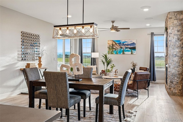 dining room featuring baseboards, a ceiling fan, and light wood finished floors