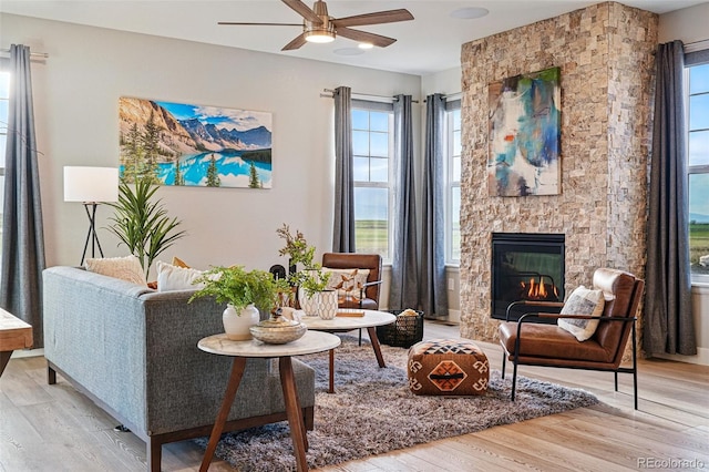 sitting room featuring light wood-style floors, plenty of natural light, ceiling fan, and a fireplace