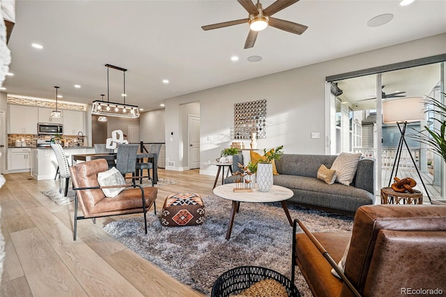 living room with a ceiling fan, baseboards, recessed lighting, and light wood-style flooring