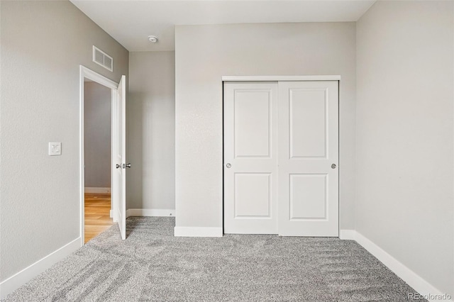 unfurnished bedroom with carpet floors, baseboards, a closet, and visible vents