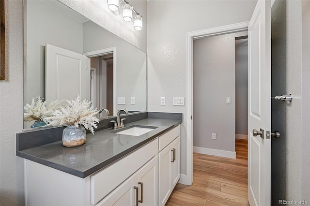 bathroom featuring vanity, baseboards, and wood finished floors