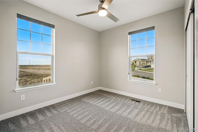 carpeted empty room featuring baseboards, ceiling fan, and visible vents