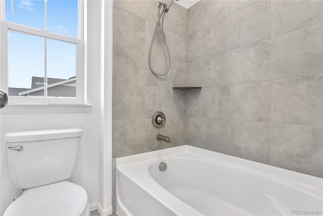 bathroom featuring toilet and tiled shower / bath