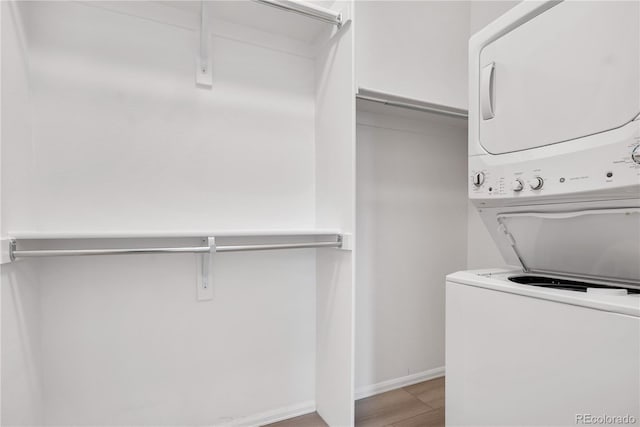 laundry area with light hardwood / wood-style flooring and stacked washing maching and dryer