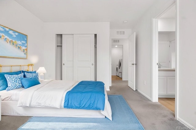 carpeted bedroom featuring washer / dryer, a closet, and ensuite bath