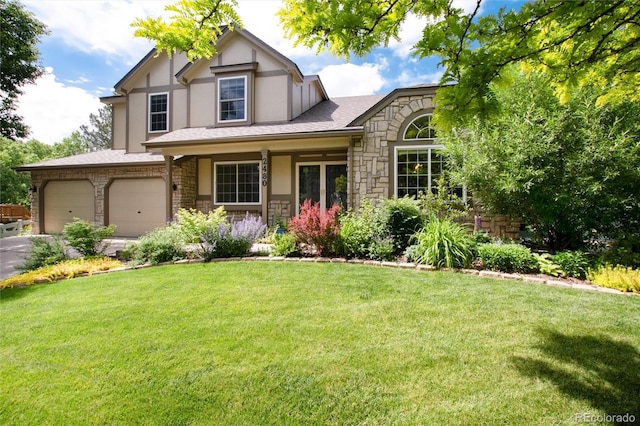 2480 W Jamison Way, Littleton, CO 80120 - tudor house featuring stone siding, a front yard, an attached garage, and driveway