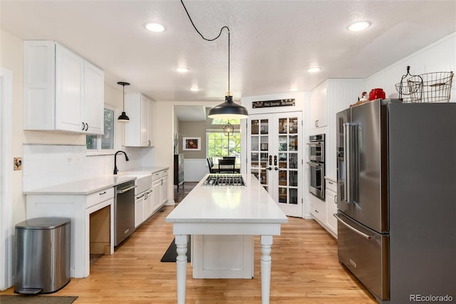 2480 W Jamison Way, Littleton, CO 80120 - kitchen with stainless steel appliances, white cabinets, a kitchen island, light wood-type flooring, and french doors