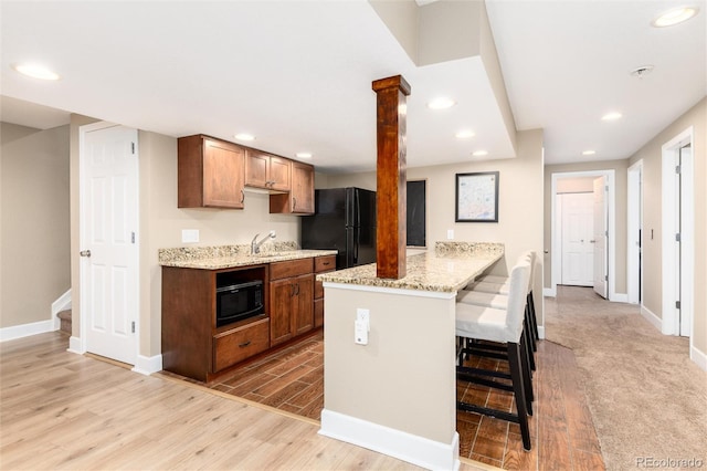 2480 W Jamison Way, Littleton, CO 80120 - kitchen with black appliances, light wood finished floors, recessed lighting, a breakfast bar area, and a peninsula