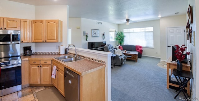 13708 Legend Trl Unit 101, Broomfield, CO 80023 - kitchen with light brown cabinetry, stainless steel appliances, a sink, a peninsula, and open floor plan
