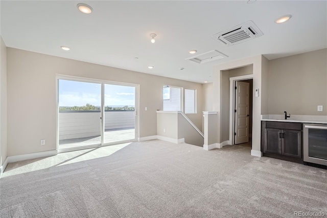 unfurnished room with light carpet, sink, and beverage cooler