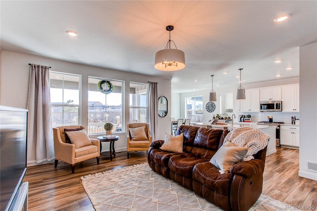 living area featuring visible vents, recessed lighting, light wood-type flooring, and baseboards