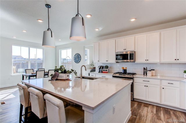 kitchen with dark wood-style floors, decorative backsplash, stainless steel appliances, and a sink