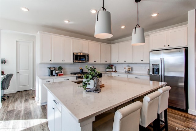 kitchen featuring a kitchen island, white cabinets, stainless steel appliances, and light wood-style floors