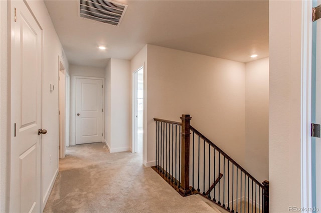 hallway with visible vents, baseboards, carpet, an upstairs landing, and recessed lighting