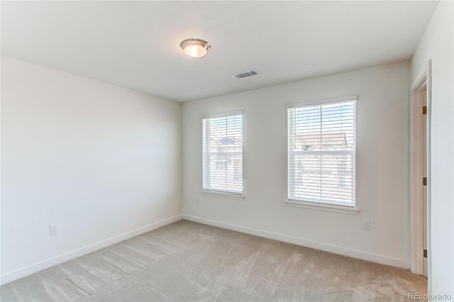 empty room with light carpet, visible vents, and baseboards