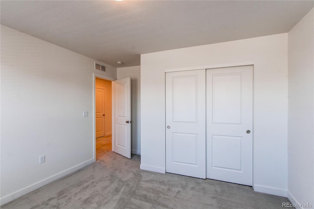 unfurnished bedroom featuring baseboards, visible vents, and light carpet