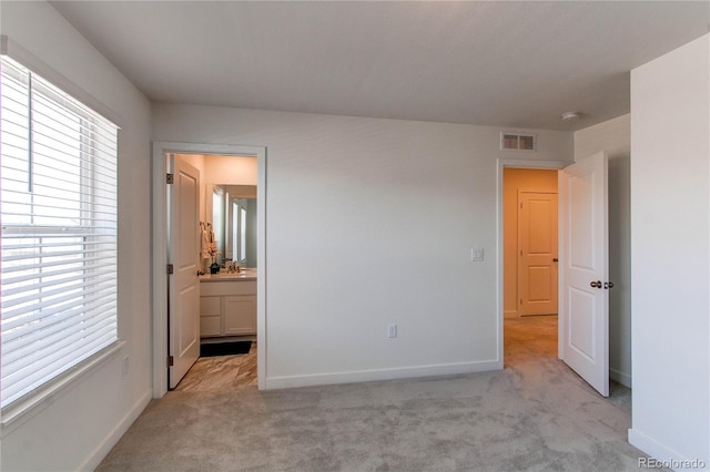 unfurnished bedroom with visible vents, light colored carpet, ensuite bathroom, and baseboards