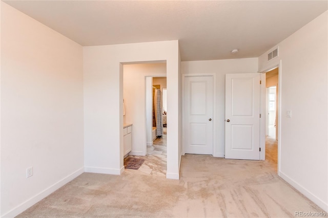 unfurnished bedroom with visible vents, light carpet, and baseboards