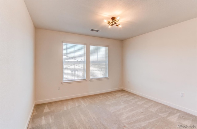 unfurnished room featuring visible vents, light colored carpet, and baseboards