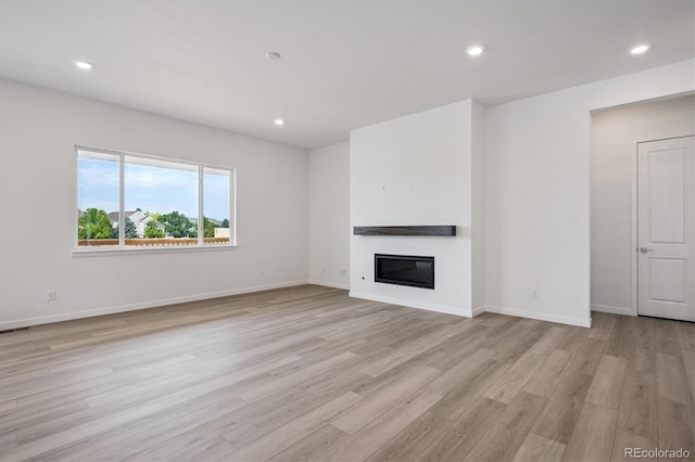9197 Ironwood St, Highlands Ranch, CO 80129 - unfurnished living room featuring light wood finished floors, a glass covered fireplace, and recessed lighting