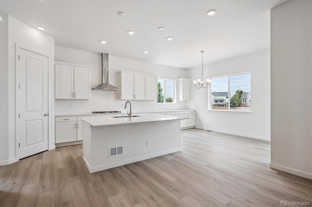 9197 Ironwood St, Highlands Ranch, CO 80129 - kitchen featuring wall chimney range hood, a kitchen island with sink, white cabinets, light countertops, and recessed lighting