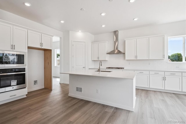 9197 Ironwood St, Highlands Ranch, CO 80129 - kitchen with stainless steel appliances, wall chimney exhaust hood, light wood-type flooring, white cabinets, and recessed lighting