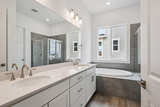 9197 Ironwood St, Highlands Ranch, CO 80129 - bathroom featuring wood finished floors, double vanity, a shower stall, a garden tub, and recessed lighting