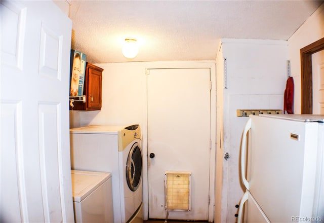 clothes washing area featuring washer and clothes dryer, a textured ceiling, and cabinets