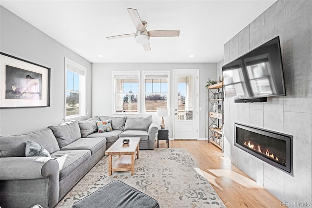 living room with a fireplace, ceiling fan, and light hardwood / wood-style floors