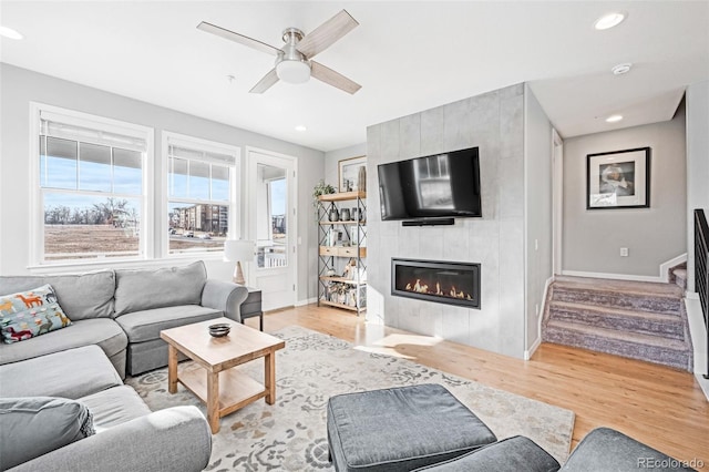 living room with a fireplace, ceiling fan, and light hardwood / wood-style floors