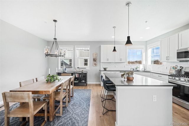 kitchen with stainless steel appliances, white cabinets, hanging light fixtures, a kitchen island, and a breakfast bar