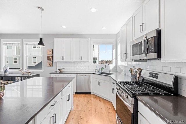 kitchen with sink, white cabinets, decorative light fixtures, tasteful backsplash, and appliances with stainless steel finishes