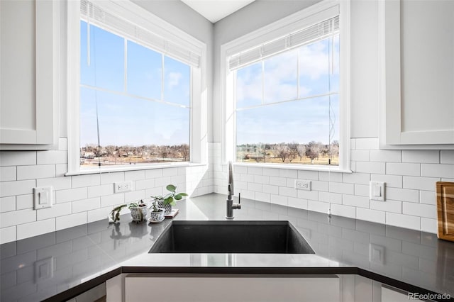 kitchen featuring sink, backsplash, and white cabinetry