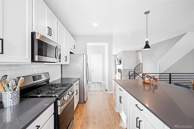 kitchen featuring stainless steel appliances, light hardwood / wood-style flooring, pendant lighting, and white cabinetry